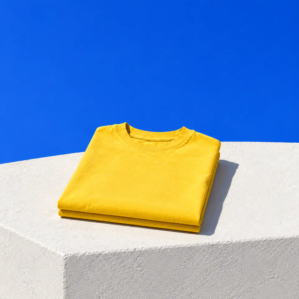 Gevouwen gele T-shirts op een witte gepleisterde trede onder een kobaltblauwe lucht